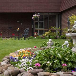 A beautifully maintained garden with colorful flowers, decorative statues, and a lush green lawn.