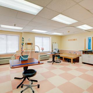 A spacious, well-lit medical clinic interior with various equipment and furniture.