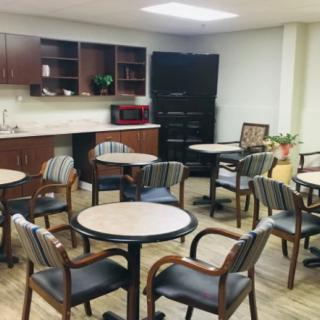 A cozy break room with several tables and chairs, a coffee machine, and storage cabinets.