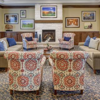 A cozy living room with patterned chairs, sofas, and a fireplace surrounded by artwork.