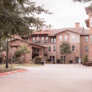A suburban residential building with a driveway and surrounding trees.