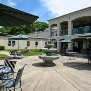 A serene outdoor courtyard featuring a decorative fountain and seating areas under green umbrellas.