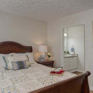 A cozy bedroom with a wooden bed, lamp, and decorative items.