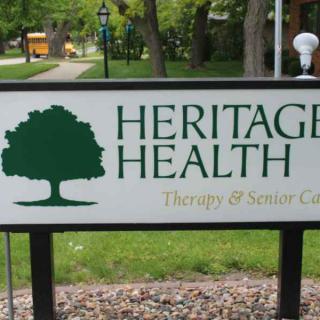 A sign for Heritage Health, indicating therapy and senior care services, featuring a tree logo.