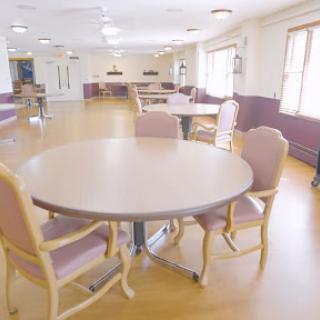 A spacious dining area with a round table and plush chairs, designed for community gatherings.