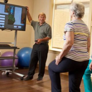 An instructor guides elderly participants through a balance and fitness exercise session.