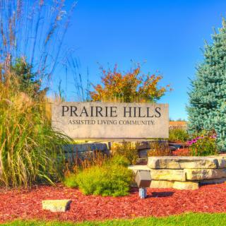 Entrance to Prairie Hills community surrounded by landscaped greenery and autumn foliage.