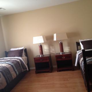 A bedroom with two twin beds and matching nightstands with lamps.