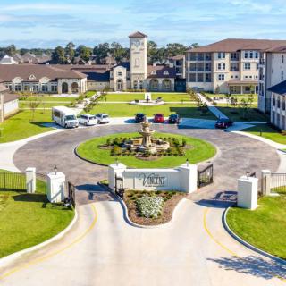 Aerial view of a residential complex featuring landscaped gardens, a central fountain, and surrounding buildings.