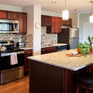 A modern kitchen featuring dark wood cabinets, stainless steel appliances, and a granite-topped island.