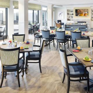A modern dining area with neatly arranged tables and chairs, featuring bright lighting and contemporary decor.