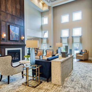 A modern living room with high ceilings, featuring elegant furniture and bright natural lighting.