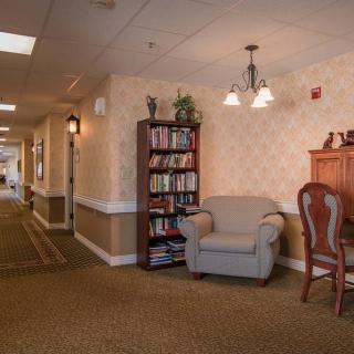 A cozy hallway with an armchair, bookshelf, and decorative lighting.