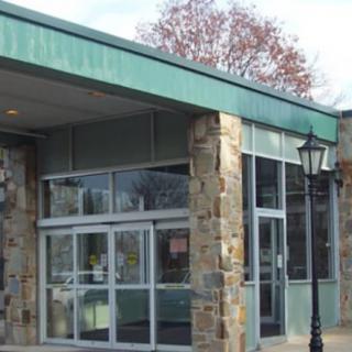 The entrance of a building featuring glass doors and a stone facade.