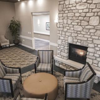 A cozy lounge area featuring a stone fireplace and a seating arrangement with four armchairs around a small round table.