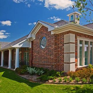A beautifully designed brick house with well-maintained landscaping under a clear blue sky.
