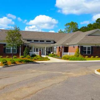 A single-story brick building with a landscaped driveway and a clear blue sky.