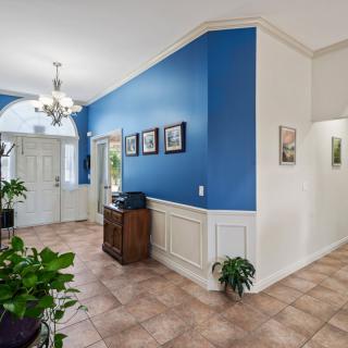 A welcoming foyer featuring a blue accent wall, chandelier, and decorative plants.