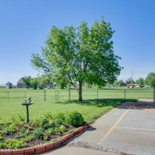 A serene backyard view featuring a lush green tree, a garden bed, and a fenced lawn under a clear blue sky.