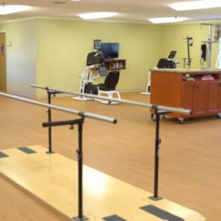 A rehabilitation room equipped with parallel bars and exercise equipment.