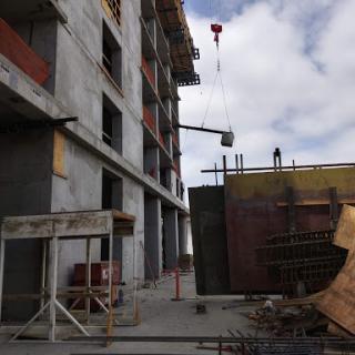 A construction site featuring a building under development, with a crane lifting materials and workers on-site.