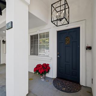 A welcoming entryway with a blue front door, a hanging lantern light, and a poinsettia plant.