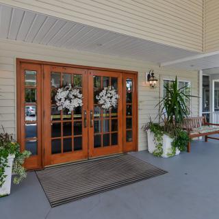 A welcoming entrance with decorative double doors, potted plants, and a bench on the porch.