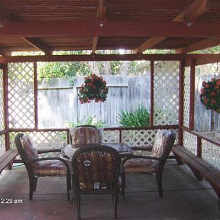 A cozy outdoor patio area with lattice walls, featuring a table and chairs under a pergola.