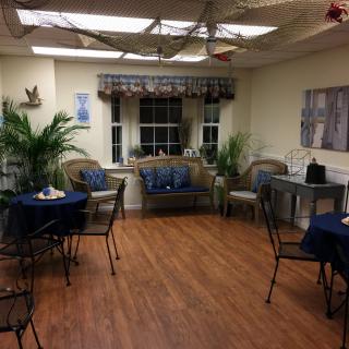 A cozy indoor seating area with tables, chairs, and a couch surrounded by plants.