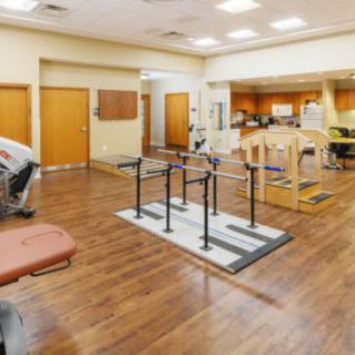 A spacious physical therapy room equipped with parallel bars and rehabilitation equipment.