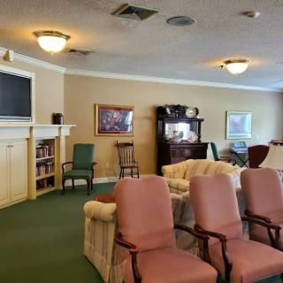 A cozy living room with various seating options, a bookshelf, and decorative paintings.