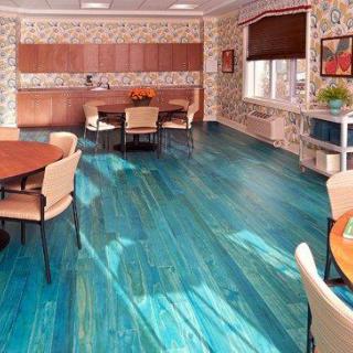 A modern dining area featuring a vibrant blue floor with wooden tables and chairs.
