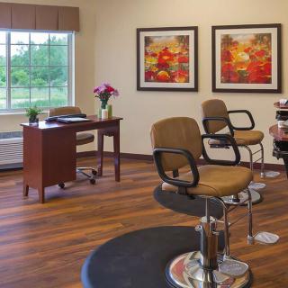 A cozy salon interior featuring styling chairs, a desk with flowers, and decorative paintings on the wall.
