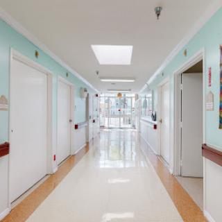 A well-lit hallway in a hospital, featuring multiple doors and a vibrant color scheme.