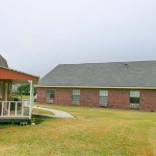 A brick house with a lawn and a gazebo in the backyard.