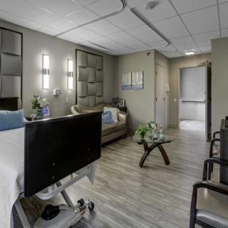 A modern and well-furnished hospital room with a patient bed, sofa, and chairs, designed for comfort.