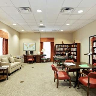 A well-furnished office space with a desk, bookshelves, and seating area.