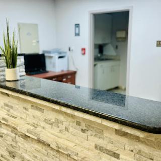 A clean and modern reception area featuring a stone counter and a potted plant.