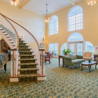 A spacious living area with a grand staircase and large arched windows.