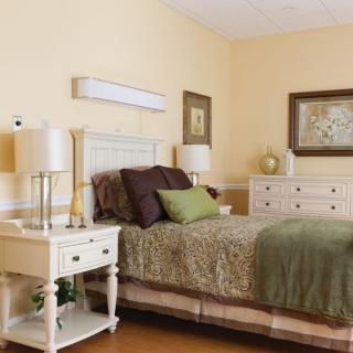 A cozy bedroom with a neatly made bed, flanked by nightstands and lamps, decorated in a warm color palette.