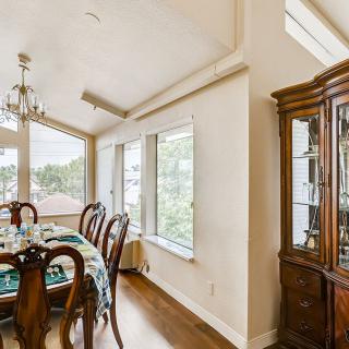A well-lit dining room with elegant wooden furniture and large windows.