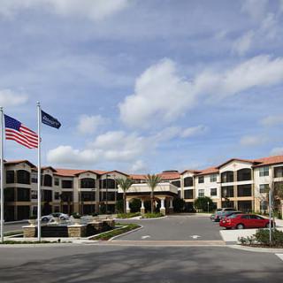 A hotel building with flags and a parking lot under a cloudy sky.