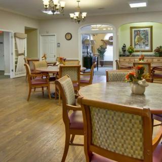 A well-lit dining area with neatly arranged tables and chairs, decorated with floral centerpieces.