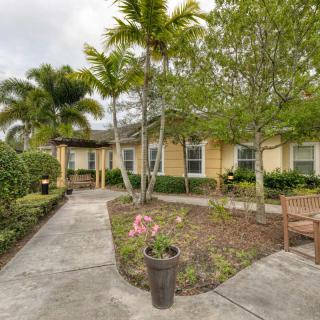 A charming residential house surrounded by lush landscaping and palm trees.