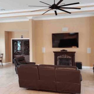 A cozy living room featuring a large sofa, wall-mounted television, and elegant fireplace.