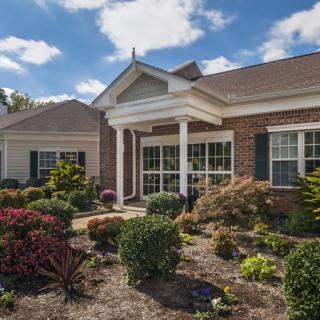 A charming brick house with well-maintained landscaping under a clear blue sky.