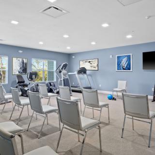 A multi-purpose room with exercise equipment and arranged chairs for a meeting or class.