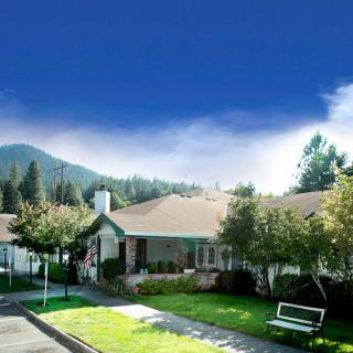 A suburban house nestled among trees with a mountain backdrop and a clear blue sky.
