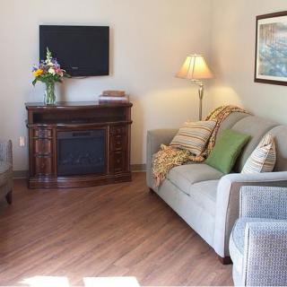 A cozy living room with a sofa, lamp, television, and decorative items.