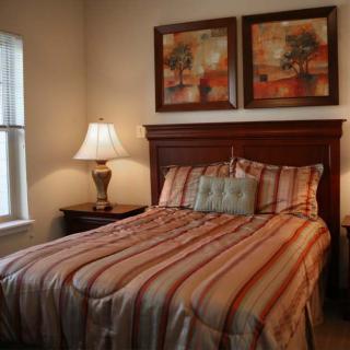 A cozy bedroom with a striped bedspread and decorative paintings above the headboard.